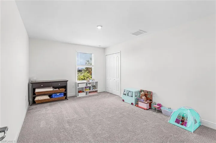 Spacious bedroom 3 featuring light gray carpeting, neutral walls, a window with blinds, and a bi-fold closet door