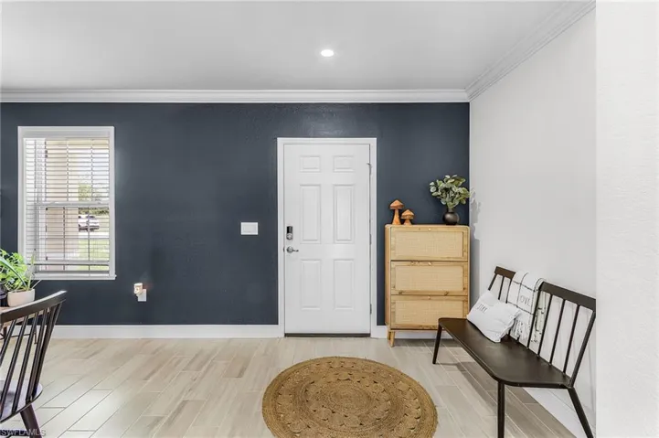 Entryway featuring a solid panel door with digital lock, a single window with blinds, and light-toned wood-finish flooring