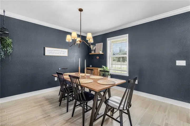 Dining area featuring a contemporary chandelier, crown molding, wood-finish flooring, and a single pane window with white blinds