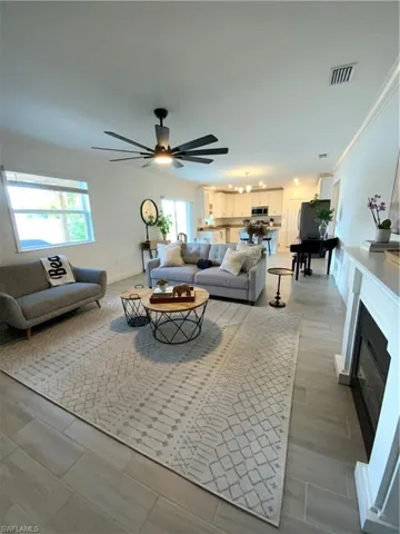 Living room with light wood finished floors, ceiling fan, and healthy amount of natural light.
