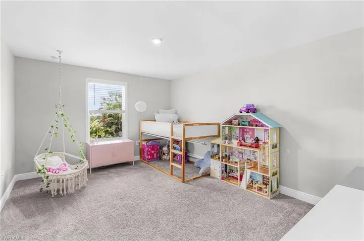 Spacious 4 bedroom featuring light gray wall paint, gray carpet flooring, a single window with blinds, ceiling light fixture, and white baseboards