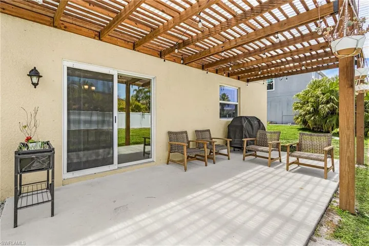 Spacious concrete patio with a slatted wood pergola, providing covered outdoor living