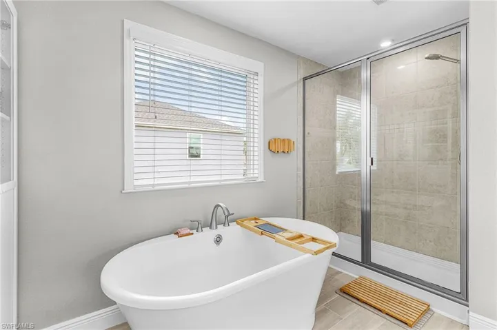 Freestanding oval bathtub with brushed nickel fixtures, complemented by a tiled walk-in shower with a glass enclosure