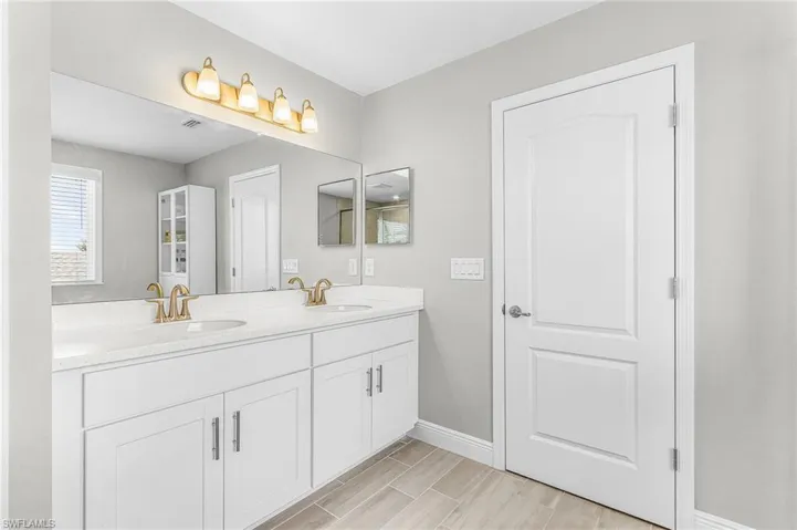 Double vanity with stone countertop, dual undermount sinks, and gold-finish faucets