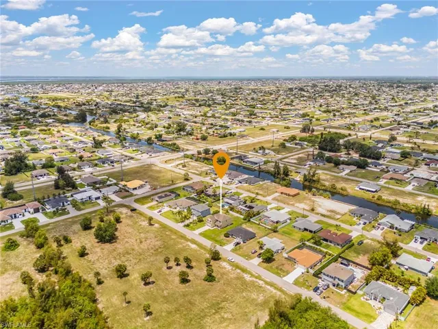 Aerial perspective showcasing a residential neighborhood with numerous single-story homes, and the ocean in the back