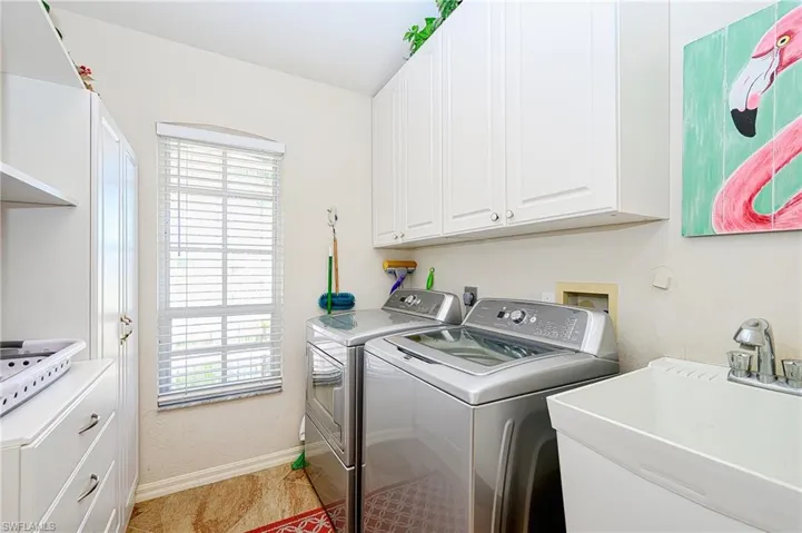 Clothes washing area featuring washer and dryer, a sink, plenty of natural light, and cabinet space