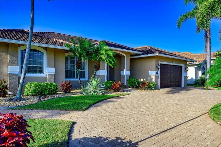 View of front of house featuring a garage, a tile roof, decorative driveway, and stucco siding
