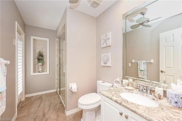 Bathroom featuring a shower stall, visible vents, a ceiling fan, toilet, and baseboards