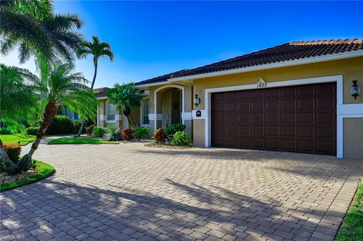 Single story home with a garage, a tile roof, curved driveway, and stucco siding