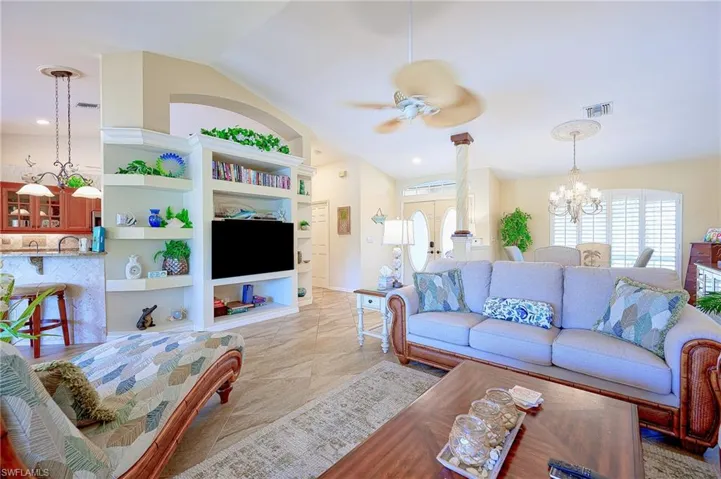 Living area with lofted ceiling, visible vents, and ceiling fan with notable chandelier