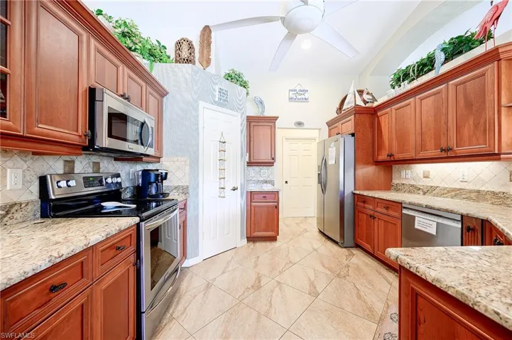 Kitchen featuring appliances with stainless steel finishes, tasteful backsplash, and light stone counters
