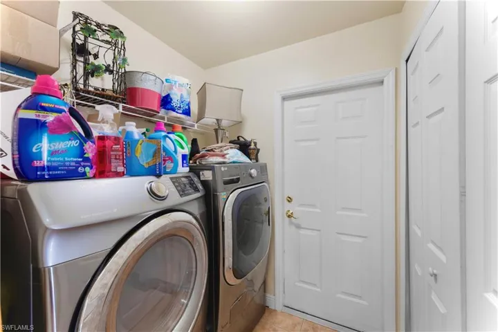 Laundry room with washing machine and dryer and light tile patterned floors