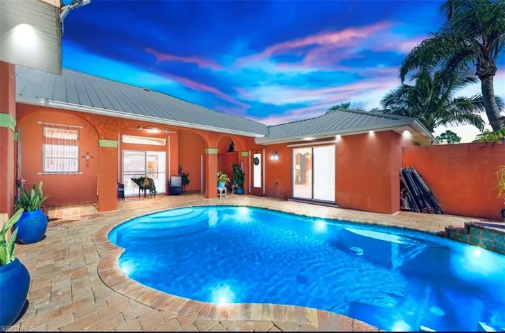 Pool at dusk featuring a patio area and ceiling fan