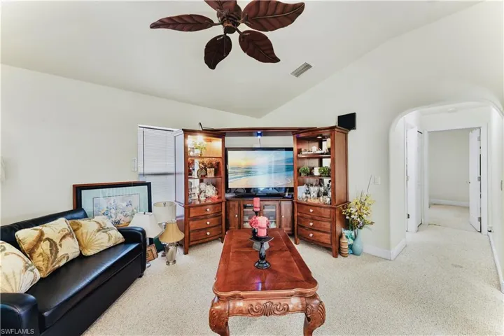Living room with a ceiling fan, lofted ceiling, and arched walkways