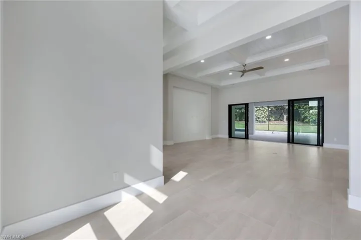 Empty room featuring coffered ceiling, ceiling fan, and beamed ceiling