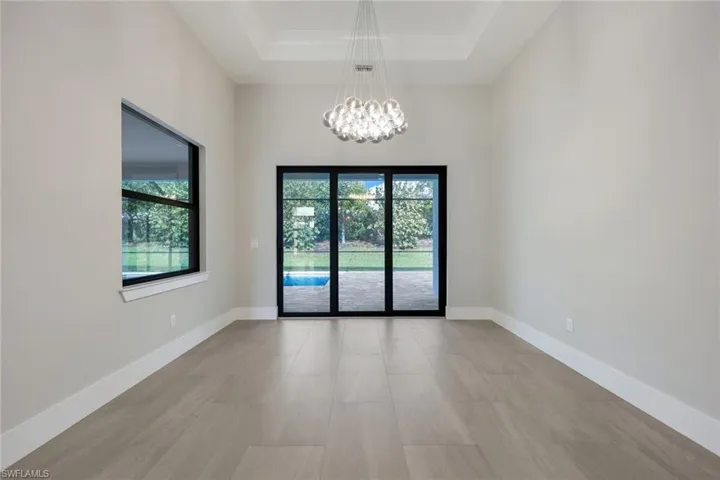 Spare room with a raised ceiling, a wealth of natural light, and a chandelier