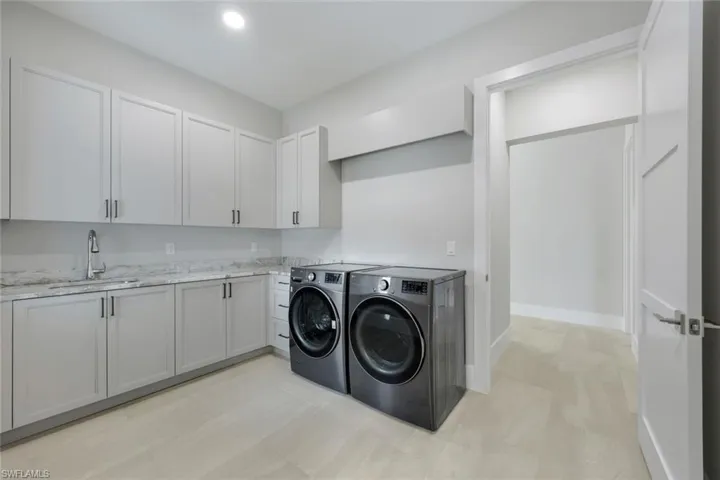 Washroom with cabinets, washer and clothes dryer, and sink