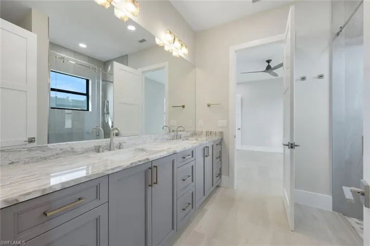 Bathroom featuring ceiling fan, vanity, and a shower with door