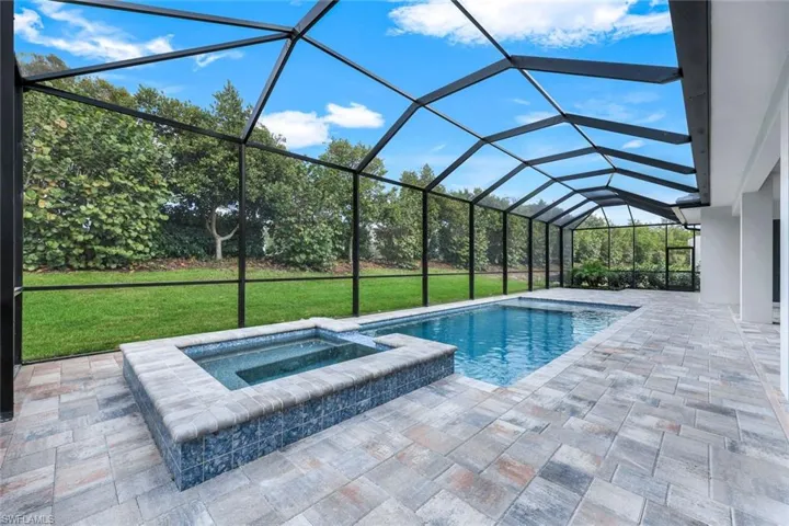 View of swimming pool featuring an in ground hot tub, a lanai, a yard, and a patio