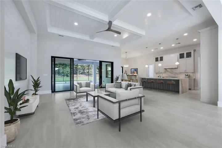 Virtually Staged Photo.  Living room featuring a ceiling fan, coffered ceiling, visible vents, a high ceiling, and beam ceiling