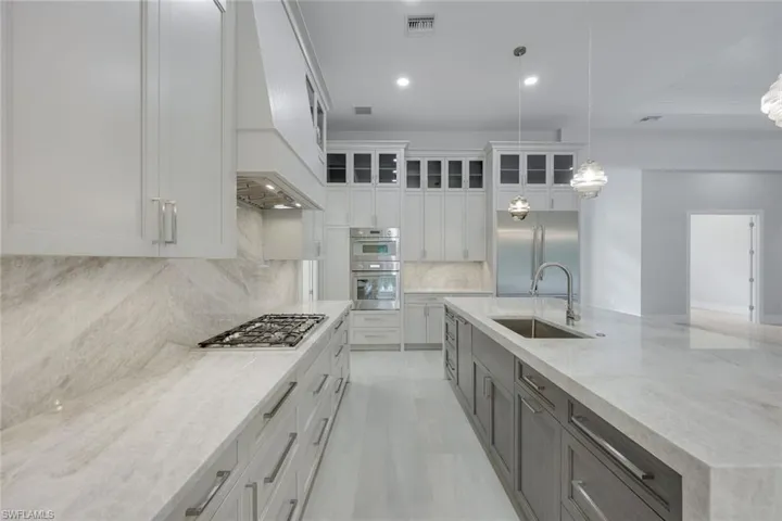 Kitchen with hanging light fixtures, white cabinetry, appliances with stainless steel finishes, and sink