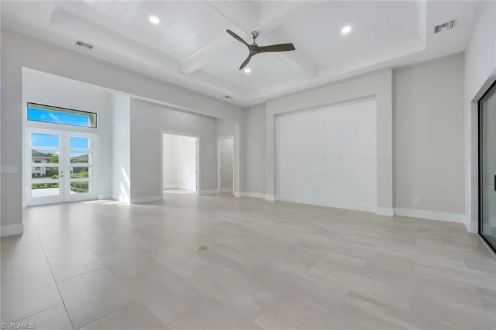 Unfurnished room with beamed ceiling, coffered ceiling, ceiling fan, and french doors