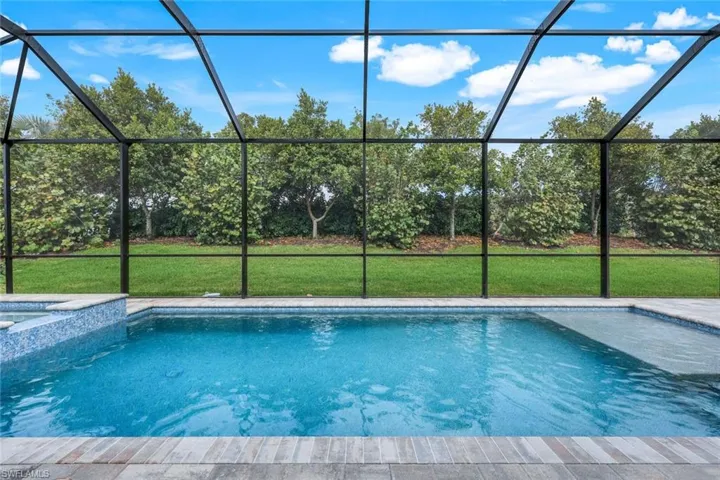 View of swimming pool featuring a lawn and glass enclosure