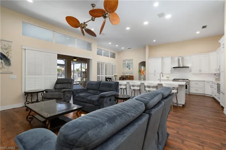 Living area with a high ceiling, dark laminate flooring, and recessed lighting