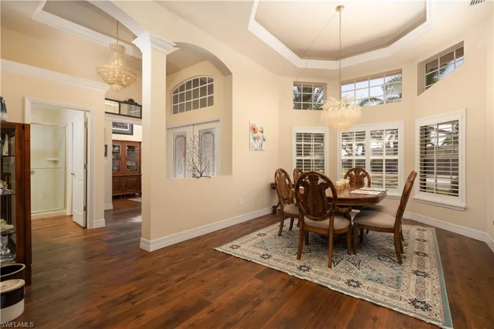 Dining room with ornamental molding, an inviting chandelier, a tray ceiling, and arched walkways