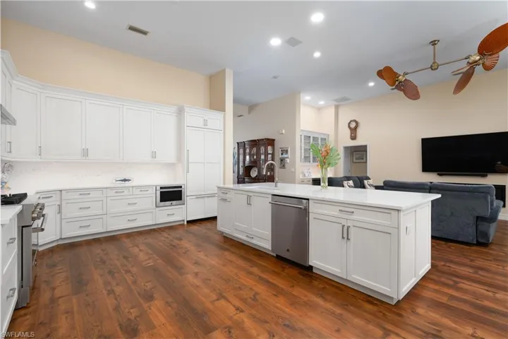 Large kitchen that opens up to living room, white cabinets and crown molding, cook island, and stainless steel appliances