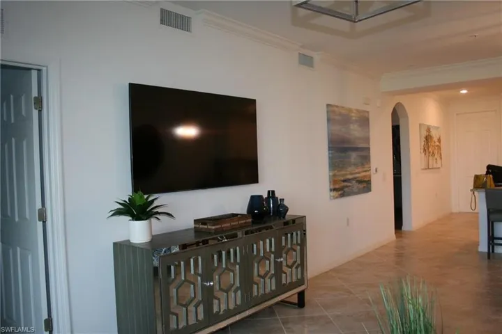 Tiled living area with ornamental molding and arched walkways