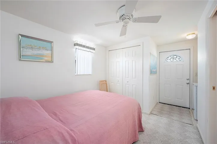Bedroom with light carpet, multiple windows, ceiling fan, and a closet
