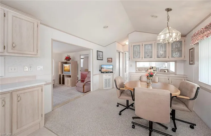 Carpeted dining area with lofted ceiling and an inviting chandelier