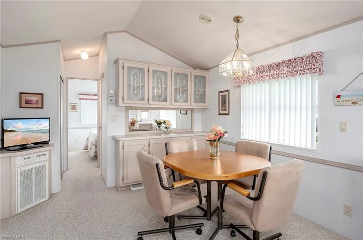 Dining room with a chandelier, vaulted ceiling, and light colored carpet