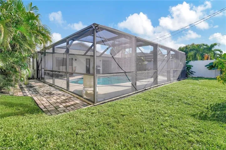 View of pool with a yard, a patio, and glass enclosure