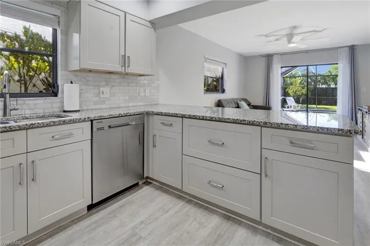 Kitchen featuring ceiling fan, sink, kitchen peninsula, and stainless steel dishwasher