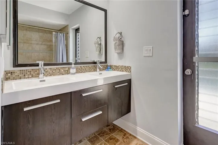 Bathroom with walk in shower, a wealth of natural light, tasteful backsplash, and vanity