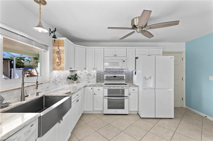 Kitchen with farmhouse style sink, gorgeous counters and backsplash.