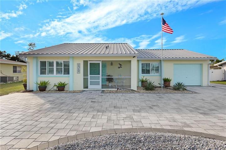 Front view of home with metal room, large screened entry and U-shaped paver driveway