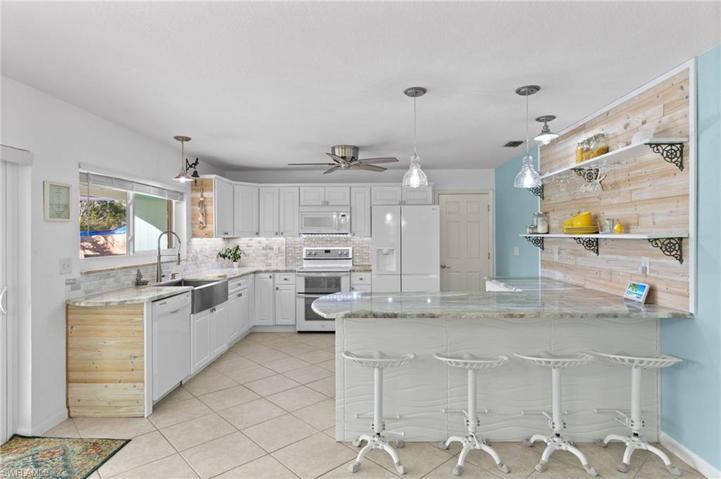 Open and airy kitchen with farmhouse style sink and breakfast bar.
