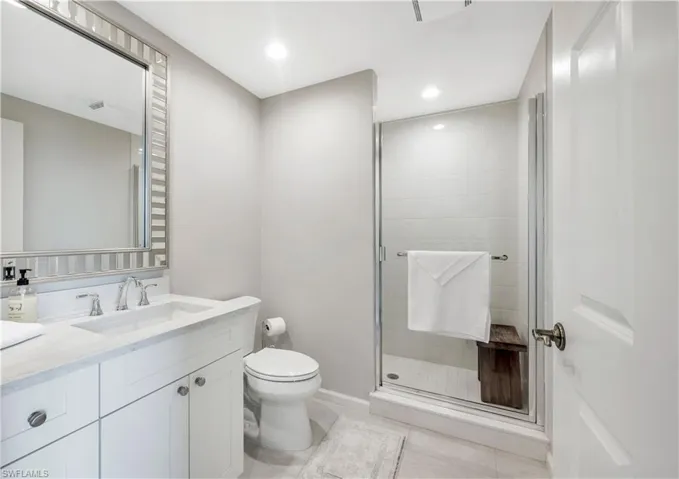 Bathroom with toilet, vanity, tile patterned floors, and a shower with shower door