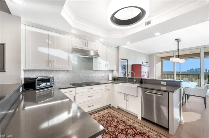 Kitchen with kitchen peninsula, dishwasher, white cabinets, and sink
