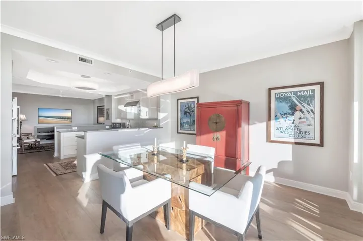 Dining area with a tray ceiling, crown molding, and light hardwood / wood-style floors