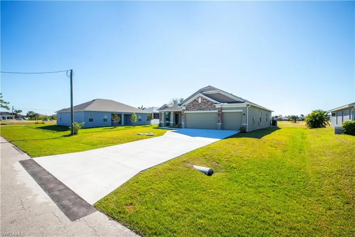 View of front of property with a garage, a front yard, and central AC