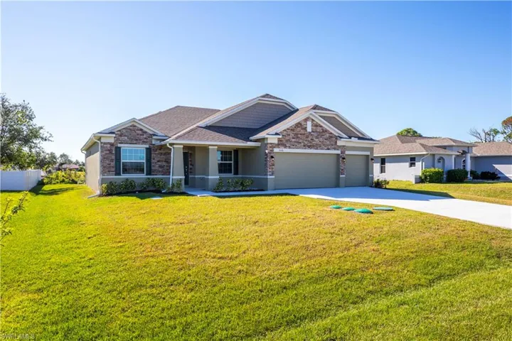 Ranch-style house featuring a garage and a front lawn