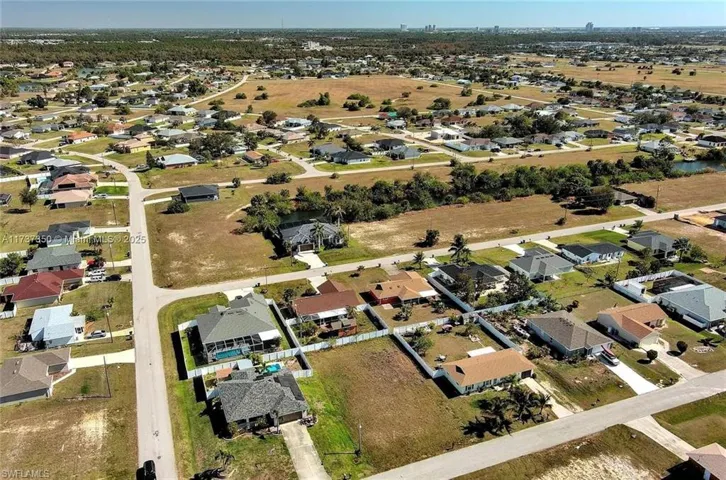 Aerial view of property and surrounding area featuring nearby suburban area