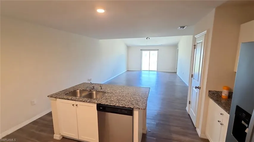 Kitchen island with a double basin sink, granite-finish countertop, and integrated dishwasher