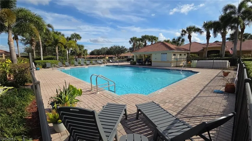 Resort-style pool with a paver deck, surrounded by lush landscaping and mature palm trees