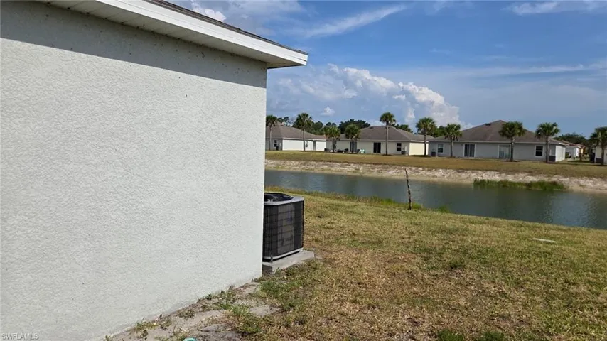 Waterfront property featuring a stucco exterior and an outdoor air conditioning unit