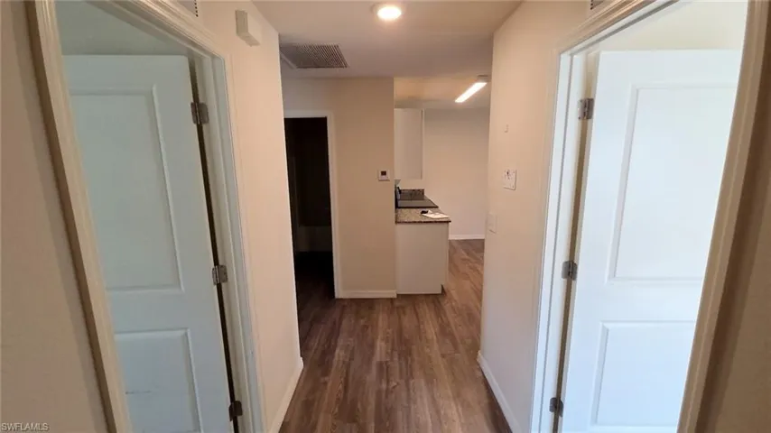 Hallway featuring wood-finish flooring, light neutral paint, and white paneled doors
